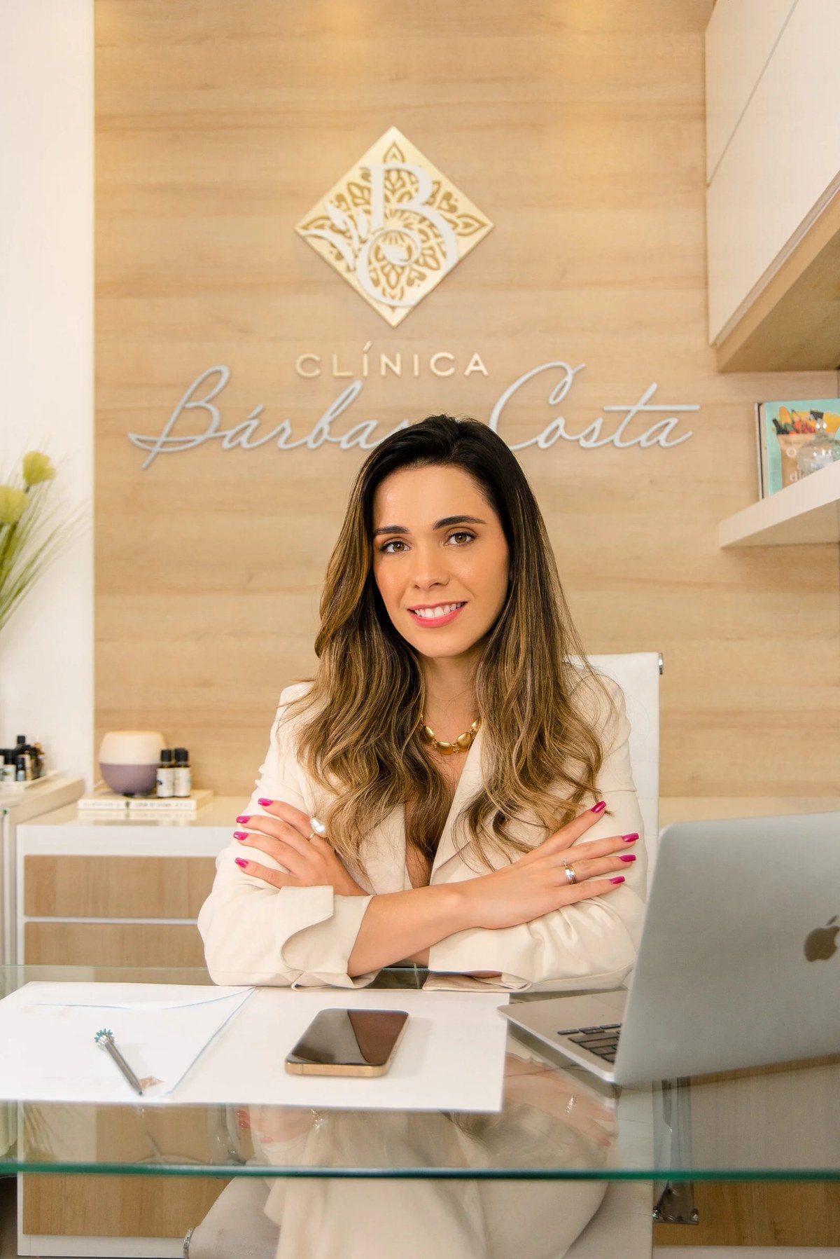 Bárbara Costa em seu consultório, com o logo da clínica ao fundo